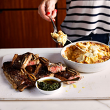 Person serving food from a dish onto a plate with a fork.