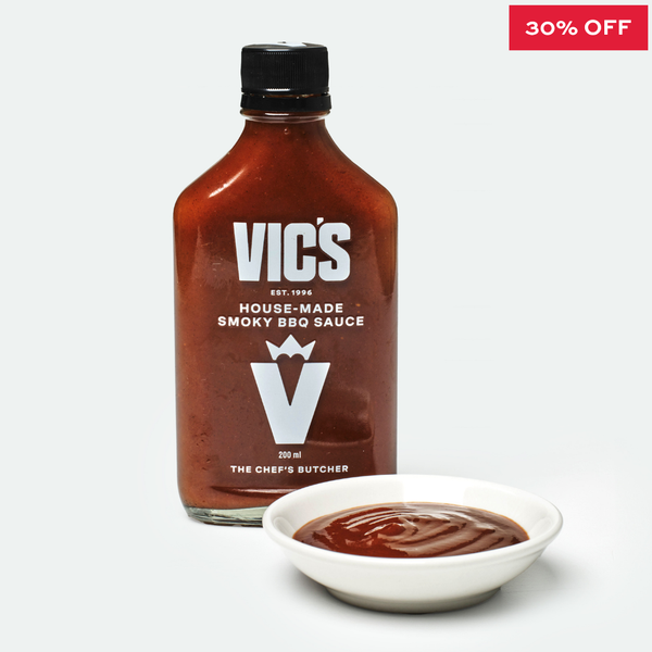 Bottle of Vic's House-Made Smoky BBQ Sauce with a bowl of sauce on a white background